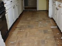 Old kitchen flooring before vinyl installation, worn and outdated appearance